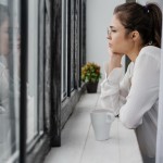 devojka zamisljeno gleda kroz prozor